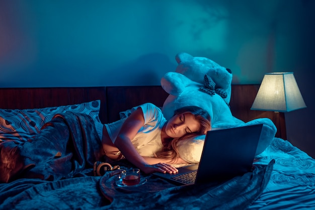 Foto joven morena durmiendo junto a su computadora portátil