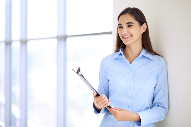 Joven morena empresaria o estudiante chica mirando a la cámara