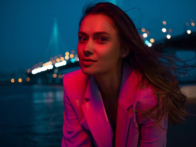 Una joven morena con estilo en las luces de la ciudad nocturna con luces de neón