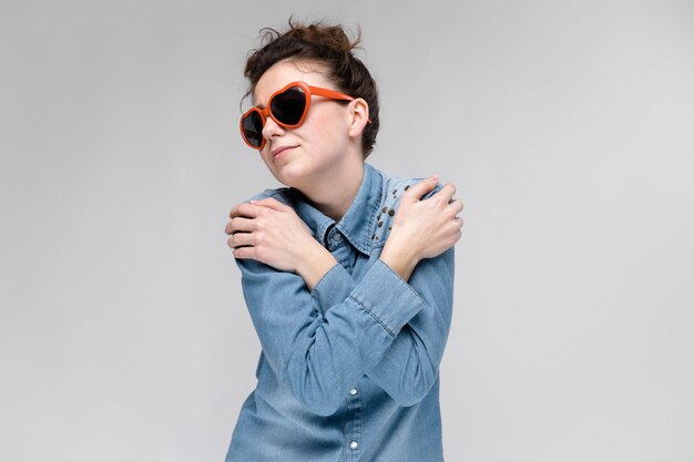 Joven morena con gafas en forma de un corazón. Los pelos se recogen en un moño.