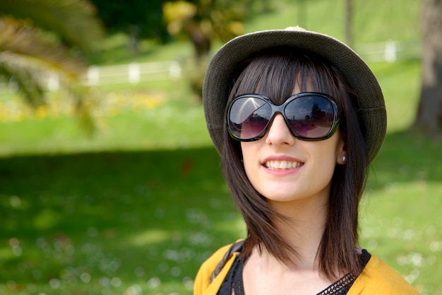 Joven morena con gafas de sol en el parque