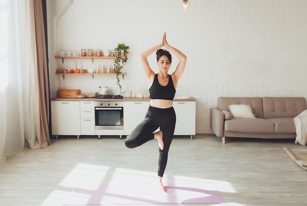 Una joven morena hace yogafitnesssports en casa