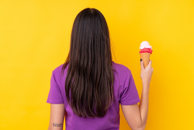 Joven morena con un helado de cucurucho en posición posterior