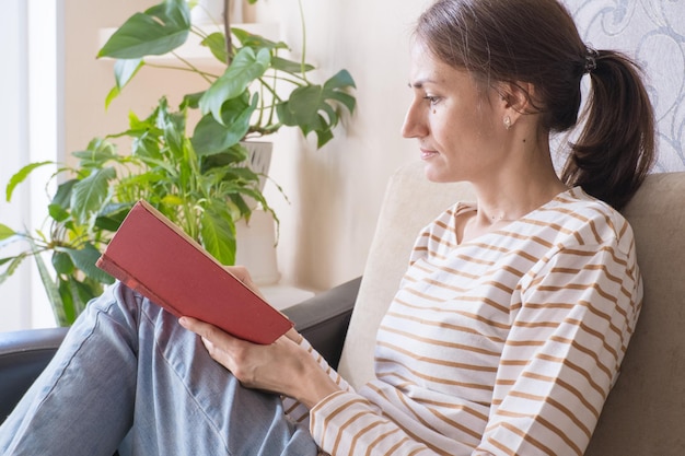 Joven morena leyendo un libro de cuentos en el sofá de casa