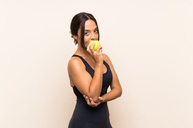 Joven morena con una manzana sobre pared aislada