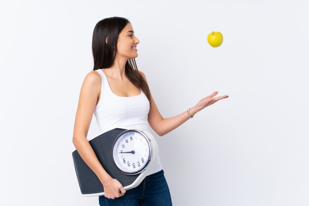 Joven morena con máquina de pesaje y una manzana