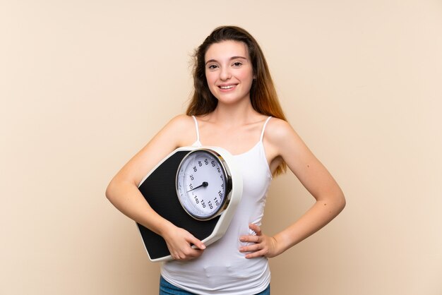 Foto joven morena con máquina de pesaje sobre pared aislada