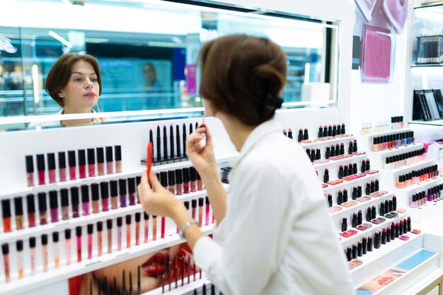 Joven morena mira reflejo en missor probando productos de belleza