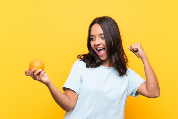 Joven morena con una naranja celebrando una victoria