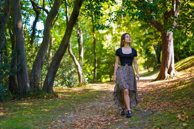Una joven morena en la naturaleza caminando por el parque natural en otoño