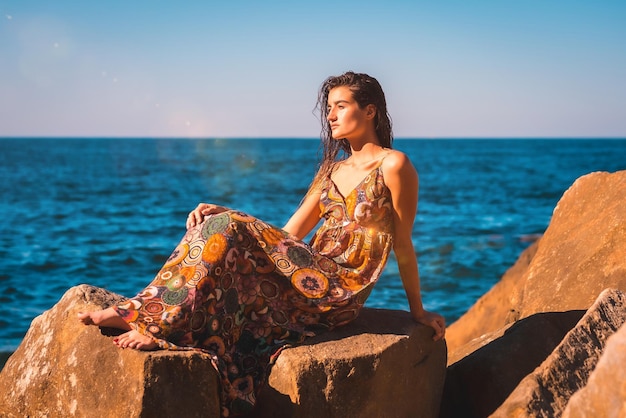 Una joven morena con el pelo mojado y un vestido floral junto al estilo de vida de verano del mar