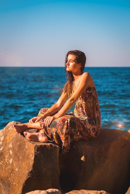 Una joven morena con el pelo mojado y un vestido floral junto al estilo de vida de verano del mar