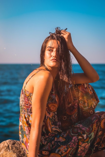 Una joven morena con el pelo mojado y un vestido floral junto al estilo de vida de verano del mar