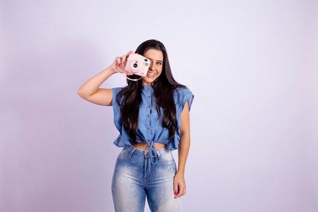 Una joven morena posa con una cámara polaroid foto de alta calidad