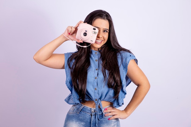 Una joven morena posa con una cámara polaroid foto de alta calidad