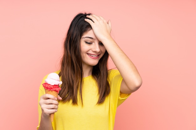 La joven morena que sostiene un helado de cucurucho sobre la pared rosada se ha dado cuenta de algo y tiene la intención de encontrar la solución