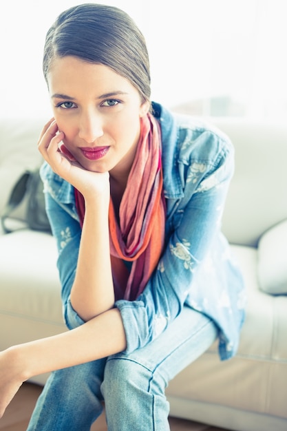 Joven morena sentada en el sofá sonriendo a la cámara