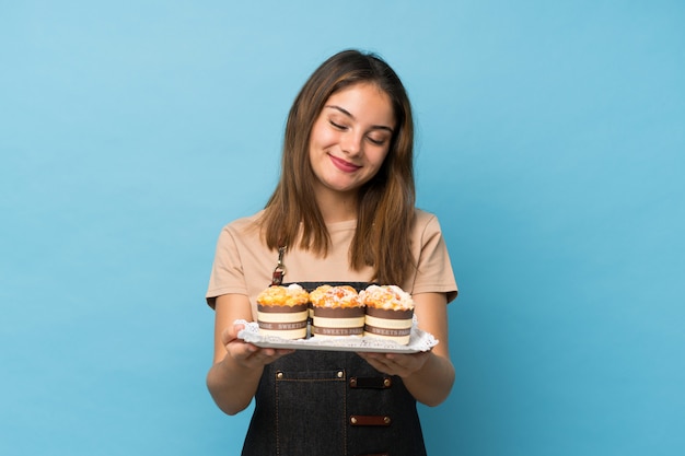 Joven morena sobre azul aislado con mini tortas