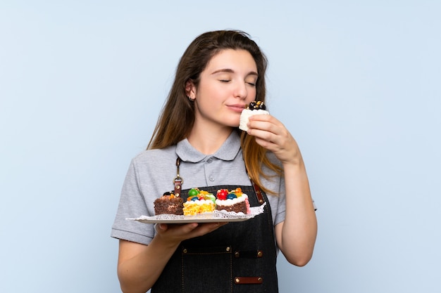 Joven morena sobre pared azul aislada con mini tortas