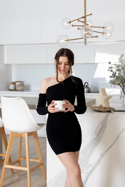 Joven morena solitaria sosteniendo una taza de té en la cocina