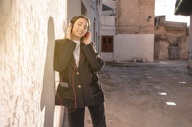 Foto joven morena soñando con confianza escuchando música en la calle