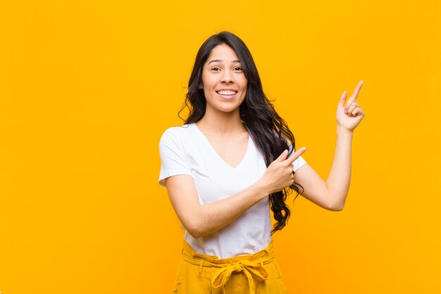 joven morena sonriendo alegremente y apuntando al lado