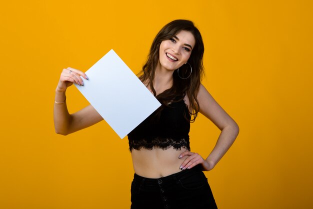 Joven morena con una sonrisa y grandes ojos posando sobre fondo amarillo