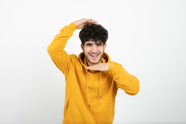 joven morena en sudadera con capucha amarilla de pie y posando.