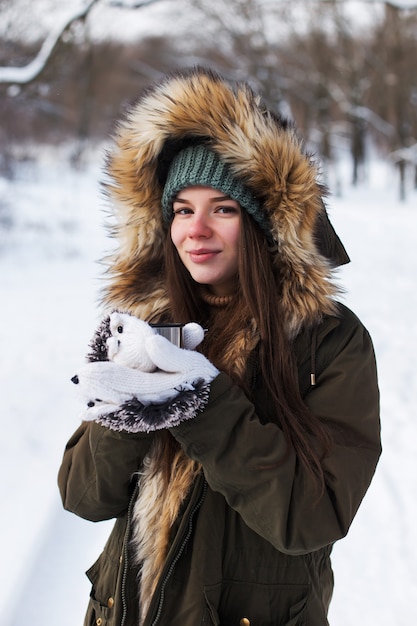 Una joven, morena, con suéter, un sombrero y una chaqueta verde, en el contexto del paisaje invernal. Nieve y heladas, el concepto de Navidad.