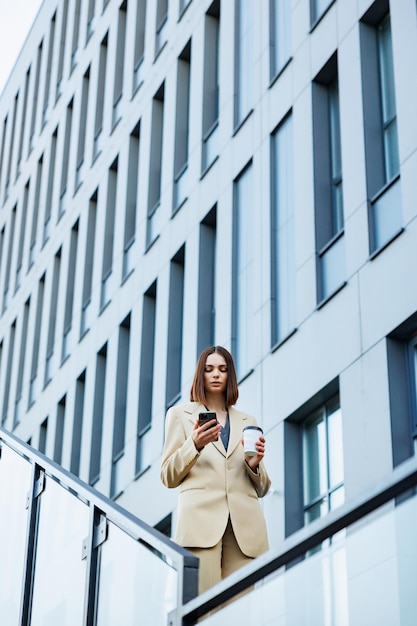 Una joven morena con el telón de fondo de un centro de oficinas del centro de negocios Retrato de un traje informal de café inteligente de inicio exitoso