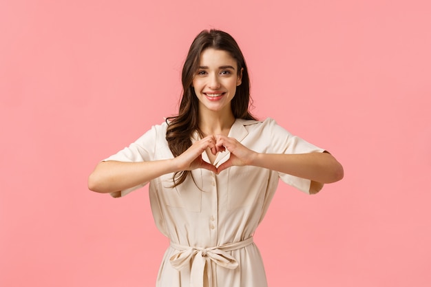 joven morena vestida, mostrando el signo del corazón