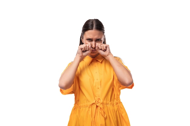 Una joven morena vestida con un vestido amarillo de verano está angustiada y quiere llorar