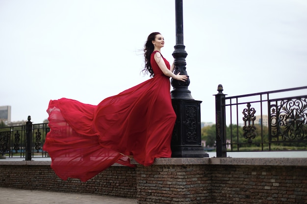 Joven morena en un vestido rojo con un tren