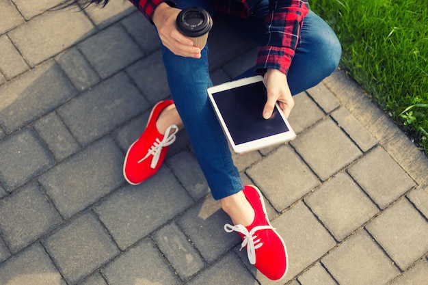 Joven morena womanwith tablet sirviendo en internet sobre el césped