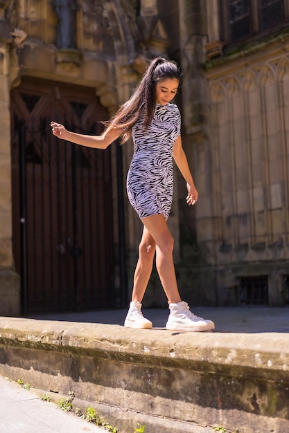 Joven morenita posando en la puerta de una iglesia en verano usando un mono con estampado de cebra