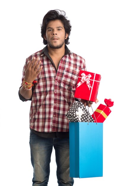 Joven mostrando rakhi en su mano con bolsas de compras y caja de regalo con motivo del festival Raksha Bandhan.