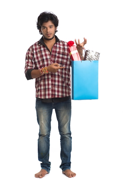 Joven mostrando rakhi en su mano con bolsas de compras y caja de regalo con motivo del festival Raksha Bandhan.