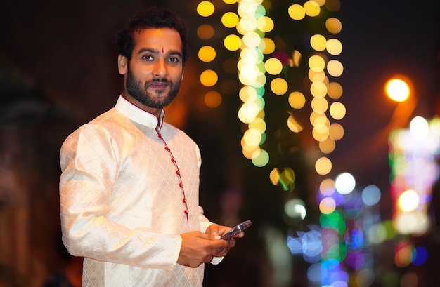 Joven con móvil en imagen nocturna con vestido tradicional y hermoso fondo