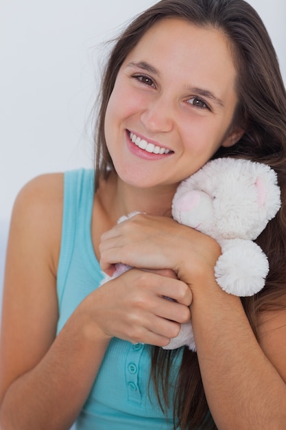 Joven mujer abrazando a un pequeño oso de peluche