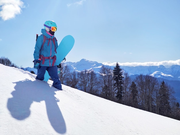 Foto joven mujer activa de pie con tabla de snowboard sobre nieve polvo en el fondo panorámico de las montañas