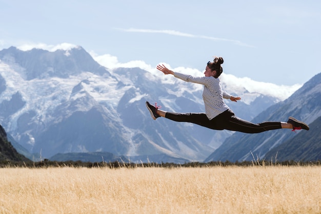 Joven mujer aficionada al yoga y la gimnasia haciendo un salto dividido perfecto en la naturaleza salvaje.