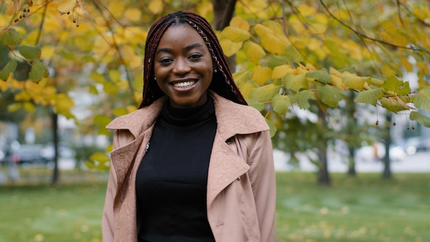 Joven mujer africana feliz positiva de pie en el parque de otoño mirando a la cámara asintiendo positivamente con la cabeza