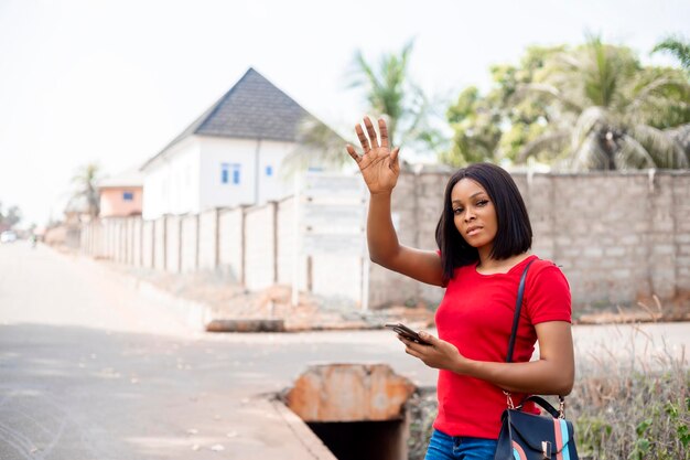 Joven mujer africana de negocios con un teléfono inteligente llamando a un taxi