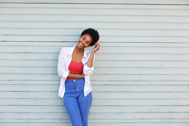 Joven mujer africana sonriendo con la mano en el cabello