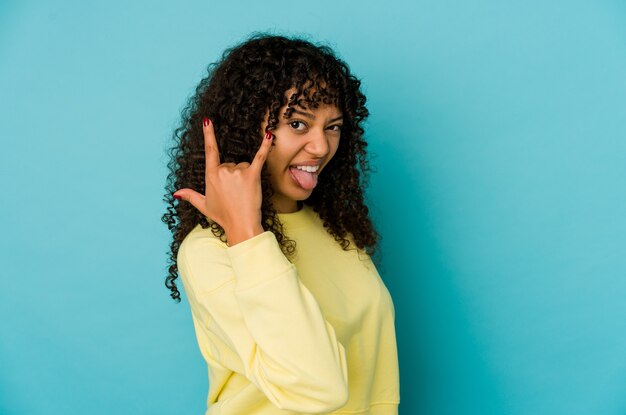 Joven mujer afro aislada mostrando gesto de rock con los dedos