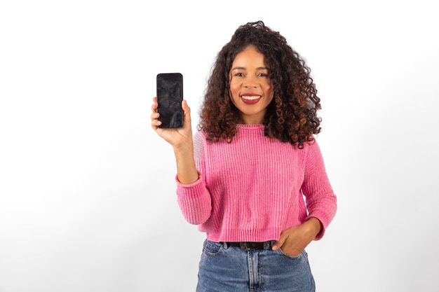 Joven mujer afro con cabello rizado sostiene un teléfono inteligente con la pantalla en blanco con espacio para copiar