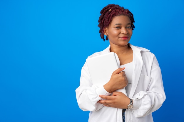 Joven mujer afro se enrolla la manga contra la superficie azul