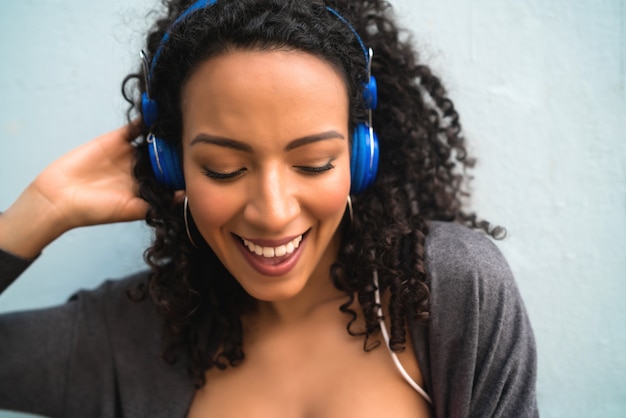 Joven mujer afro escuchando música con auriculares