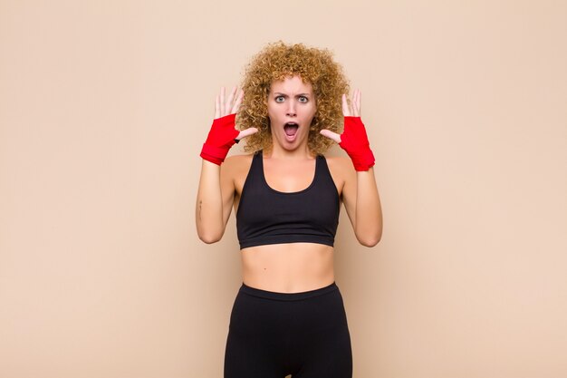 Joven mujer afro gritando con las manos en el aire, sintiéndose furioso, frustrado, estresado y molesto concepto deportivo