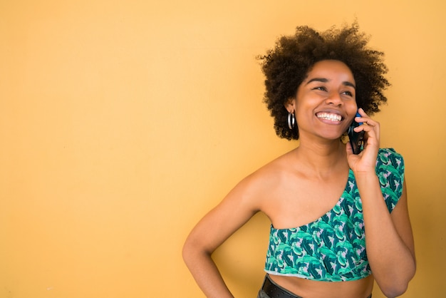 Joven mujer afro hablando por teléfono.